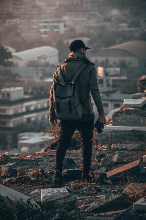an image of a male photographer from behind holding a camera in his right hand