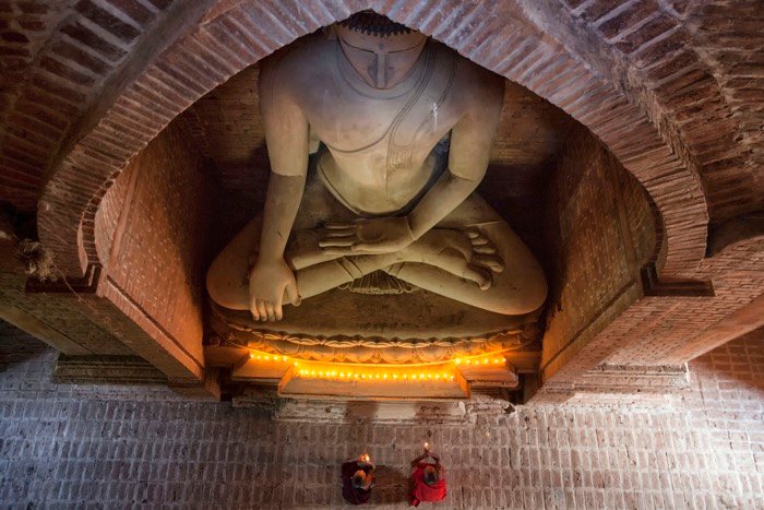 Overhead view of Buddhist monks praying under a statue of Buddha - travel photography accessories