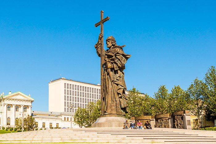 a group of people sitting underneath a tall statue on a bright clear day