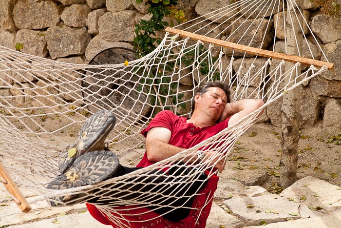 a man in a red t-shirt asleep in a netted hammock - avoid the travel photography mistakes of treating a trip as just a holiday