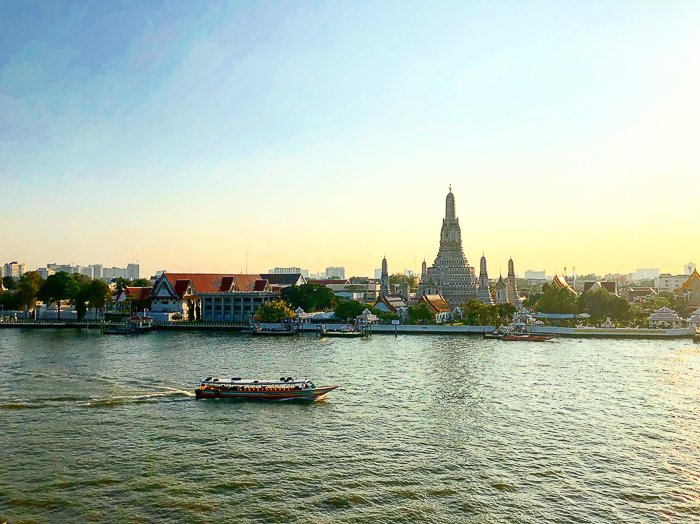 A pretty picturesque cityscape by a river on a bright day at the moment a colourful boat goes by