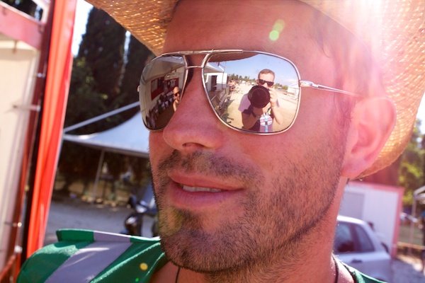 A man in a straw hat reflecting the photographer in his sunglasses