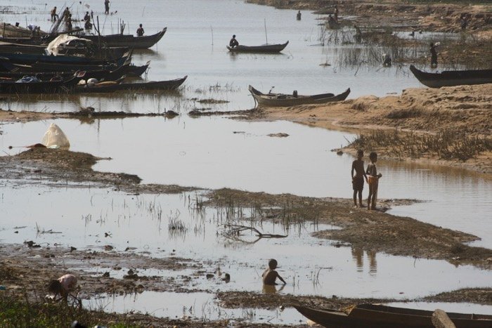 Travel photography showing people living in extreme poverty. River scene with wooden fishing boats and people
