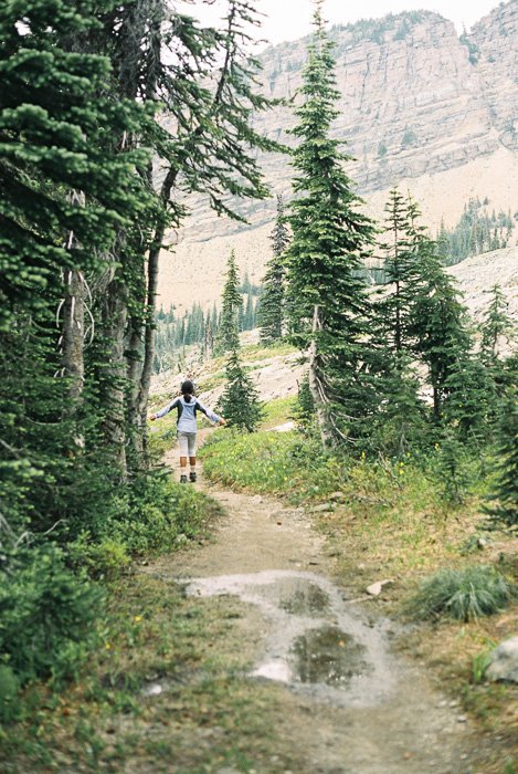 Photo of a girl taking a walk in a lucious forest and mountain landscape