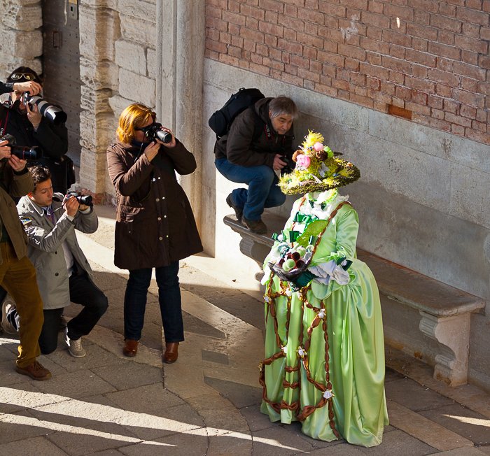 A crowd photographing a green costumed carnival exhibit