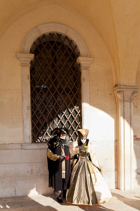 A portrait of two carnival performers standing under a window