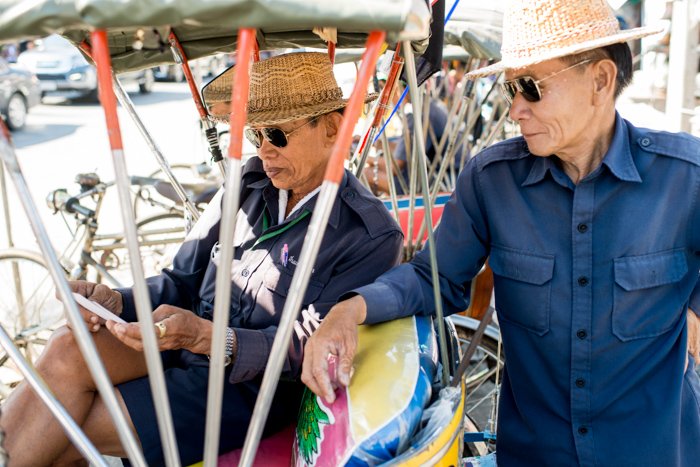 A documentary photography shot of two samlar drivers relaxing