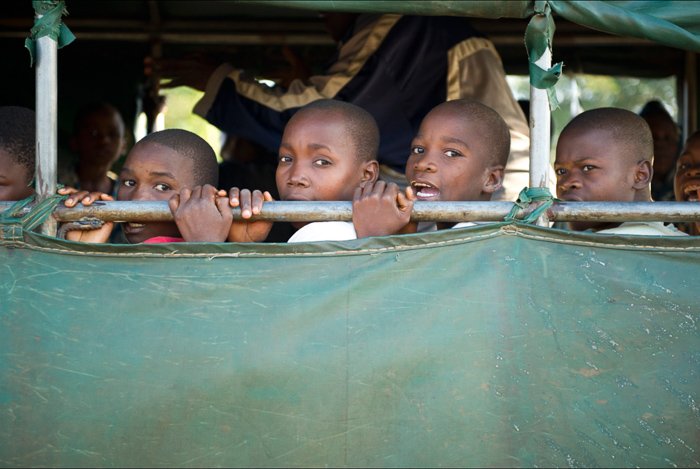 Portrait of a group of young boys behind green tarpaulin - local guide for better travel photography