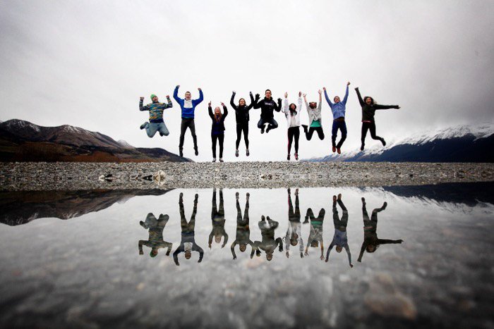 A group jumping in front of a body of water