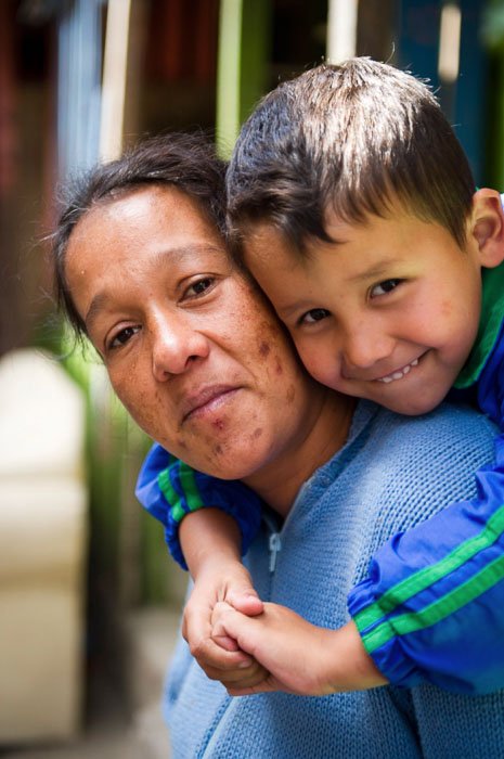 A close up portrait of a woman with a little boy on her shoulders taken by a travel photographer - should you tip for photos?