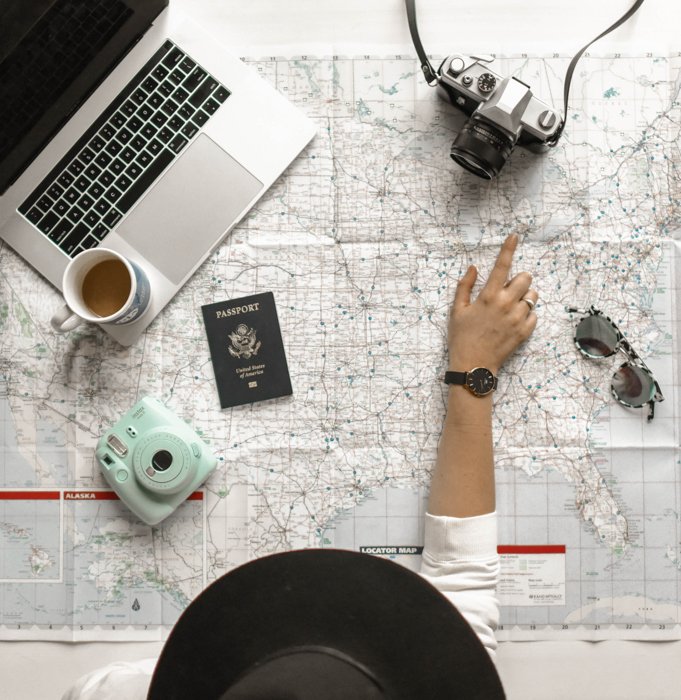 a woman pointing on a map with her travelling cameras