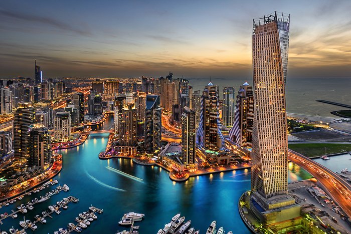 UAE cityscape at dusk, lit by golden lights, deep blue waters of the creek