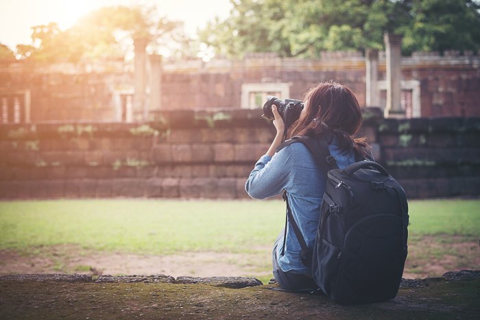 A female photographer sitting on the grass and taking a shot