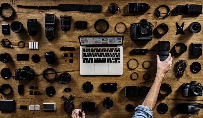Overhead view of a laptop on the table surrounded by different camera accessories