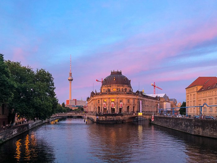 building with pillars on a river reflecting the blue, purple, and pink sunset sky